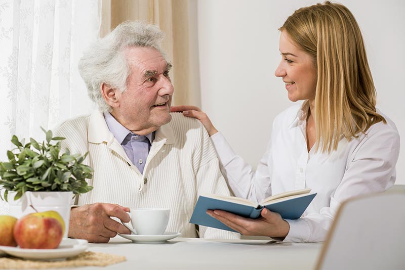 Photo of a female home care doctor signing papers with a senior man